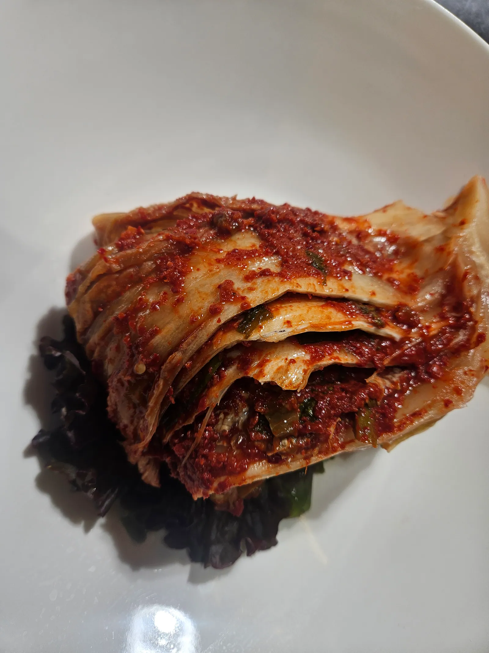 全羅道式の熟成キムチチム。白菜を一株まるごと薬味をのせて蒸し上げ、白い皿に盛ってある。