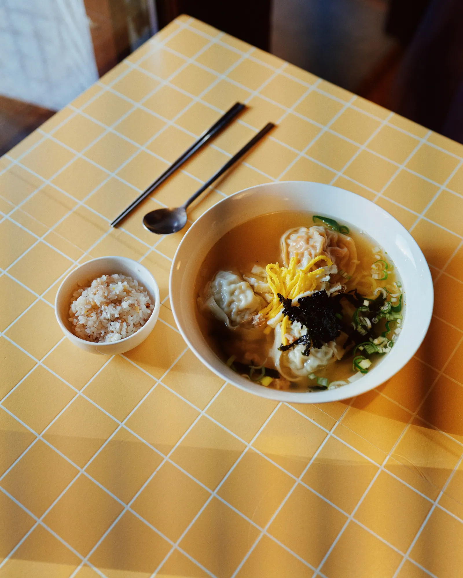 秘伝だしの手作り餃子スープ定食。澄んだだしに手包みの餃子と錦糸卵、海苔、葱を載せ、隣に麦ご飯が添えられている。