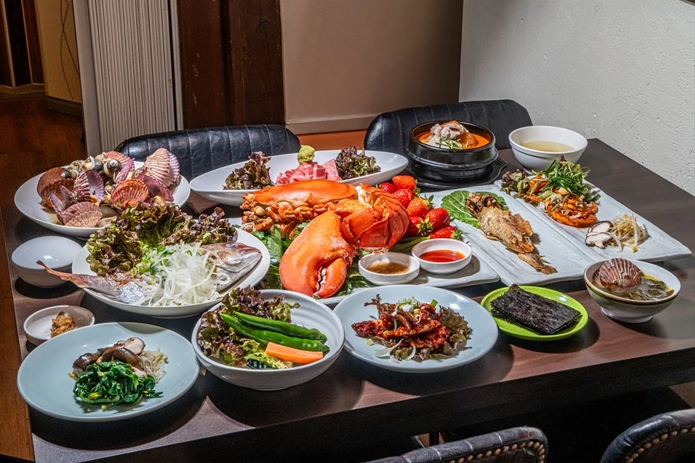 구테이블 한정식의 한상차림. 랍스터와 참치 대뱃살, 전복과 도미, 뚝배기가 흰 접시에 나뉘어 상에 가득 놓여 있다.